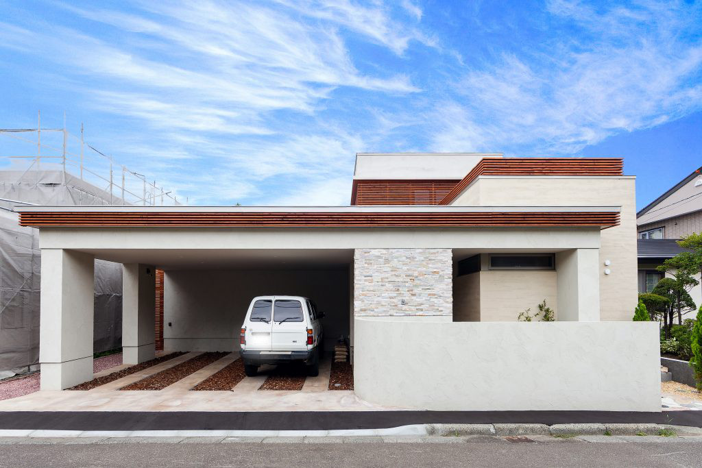 札幌市内に建つ白い外壁に石と木のアクセントを持つ住宅の外観。